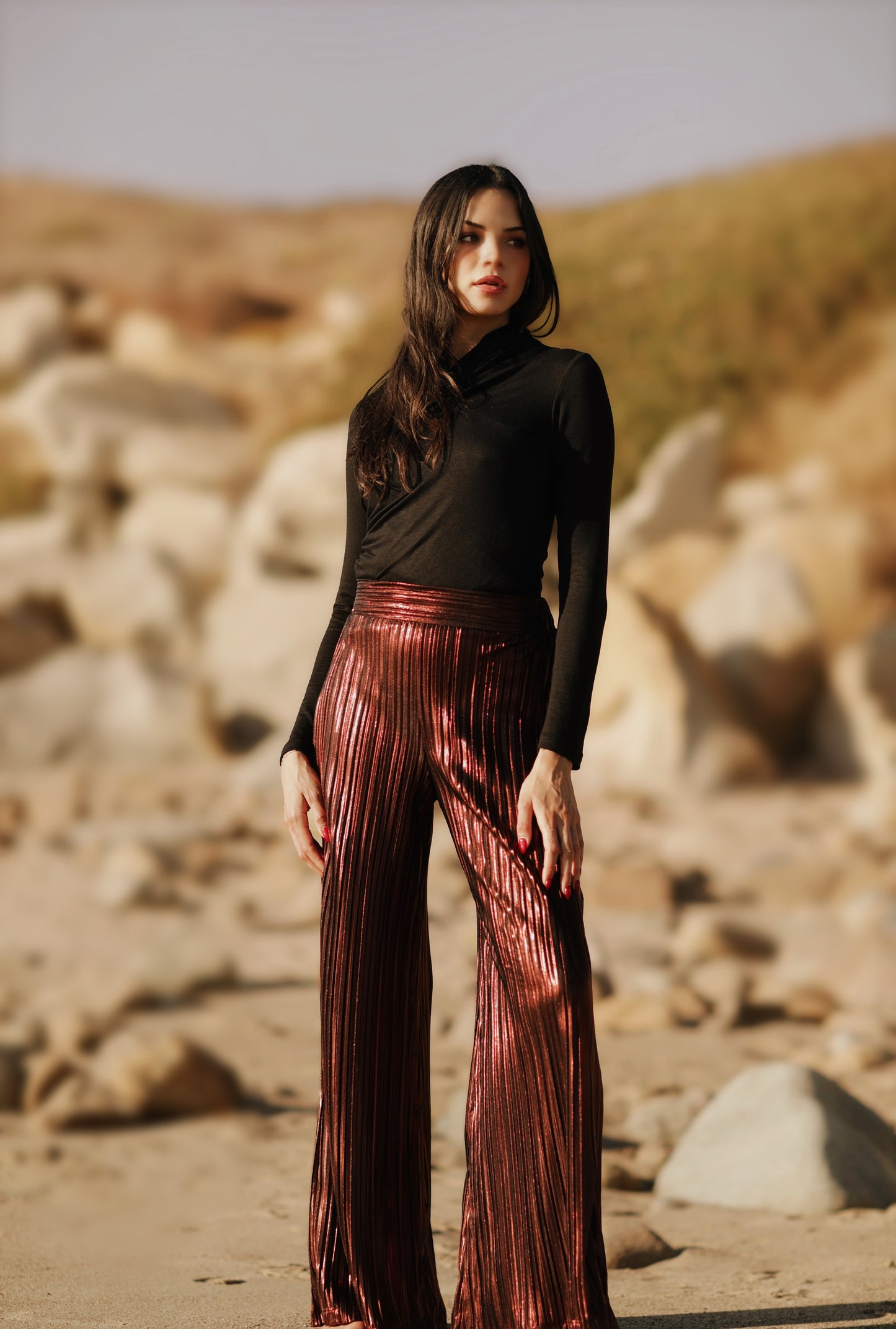 These metallic pleated wide leg pants will make any occasion sparkle. Crafted with an elastic back waistband for comfort, this loose-fit design has a high rise with a clean front waistband and flattering pleats throughout. An exclusive and elegant addition to your wardrobe. Complete the look and pair back to our Wrap Collar Top for a classic Fall look. 